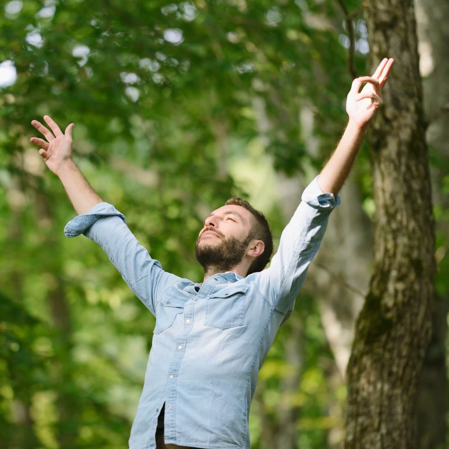 Mann, der im Wald entspannt die Arme ausbreitet und die Natur genießt.