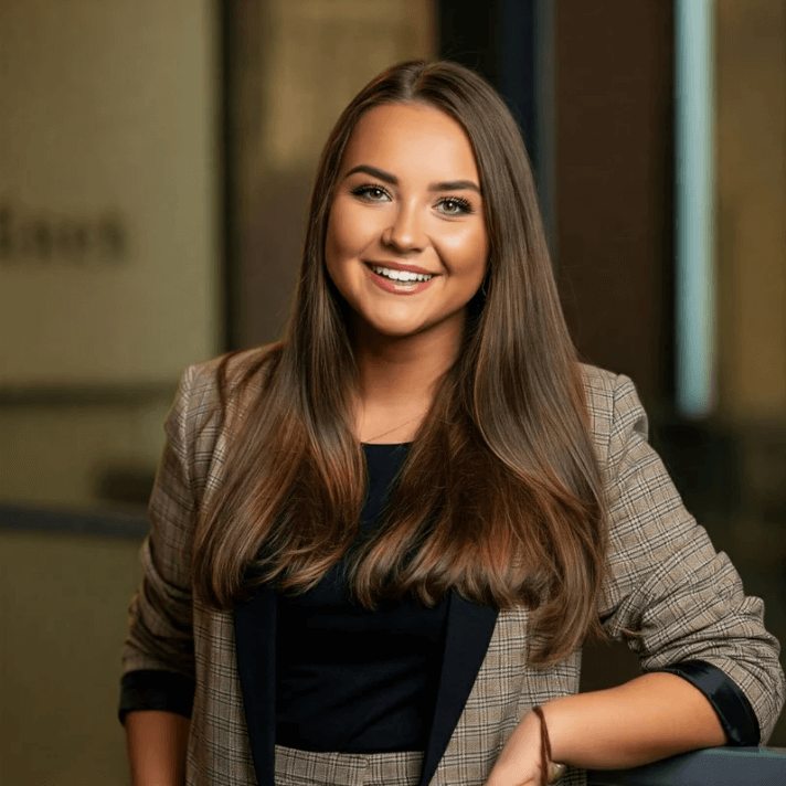 Lächelnde Frau mit langen Haaren in einem karierten Blazer, ideal für professionelle Portraits.